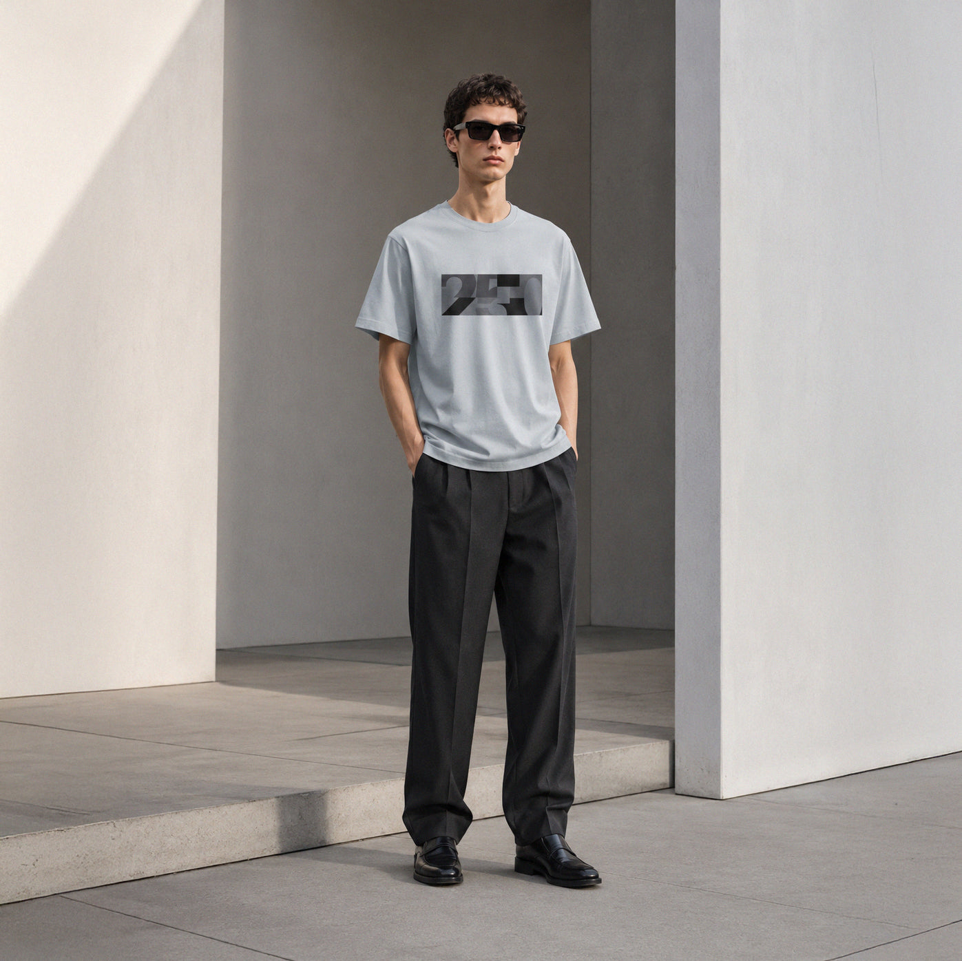 USA CREATES 250 Icon Block Tee Neutral, cement colorway worn by a man with sunglasses in a clean architectural editorial portrait