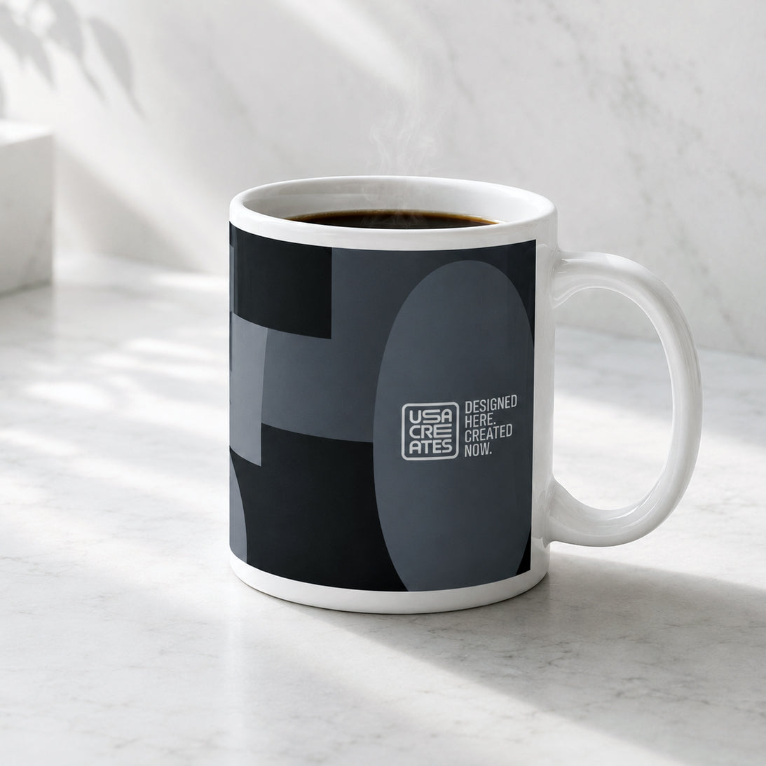 USA CREATES 250 Icon Mug Neutral, dark geometric-print ceramic mug styled on a marble kitchen counter in a modern home setting