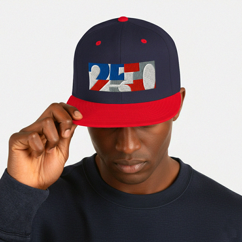 USA CREATES 250 Icon Snapback, navy and red colorway with RWB 250 embroidered icon worn by a man in a close-up outdoor editorial portrait