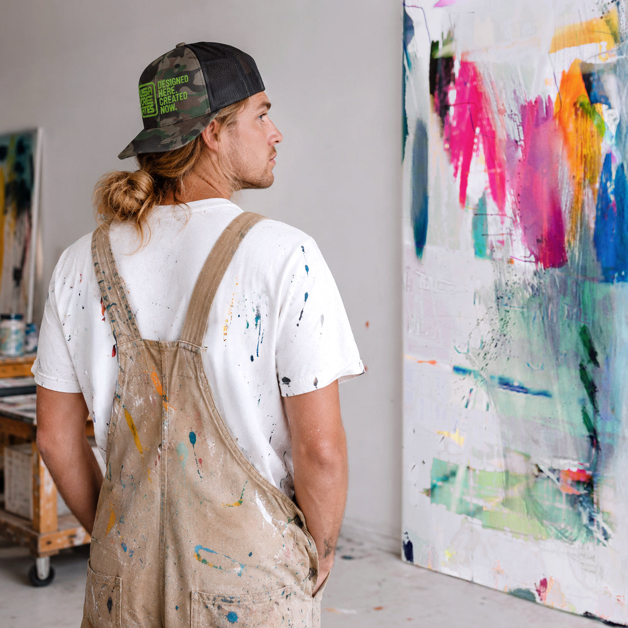 USA CREATES Camo Trucker Hat Green Stitch, shown in artist studio portrait