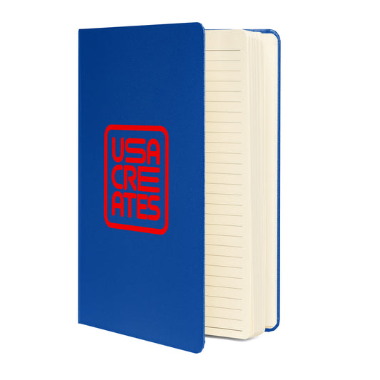 USA CREATES Signature Notebook, blue hardcover open showing interior pages with blue ribbon bookmark and back pocket detail